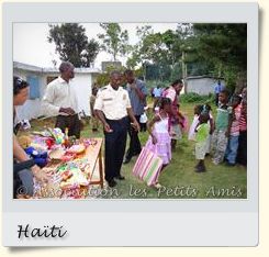Le 9 juin 2010, des bénéficiaires de l'APA se faisant distribuer des dons par les autorités locales (brigade de la protection infantile), dans le jardin à l'arrière du centre d’accueil « Les Oliviers », sur le Plateau de Salagnac, en Haïti. [Photographie vignette © Association les Petits Amis.]